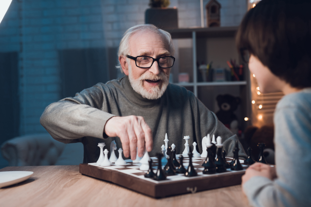 Grandfather,And,Grandson,Are,Playing,Chess,Together,At,Table,At