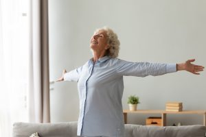 Happy,Older,Woman,With,Toothy,Healthy,Smile,Standing,With,Arms