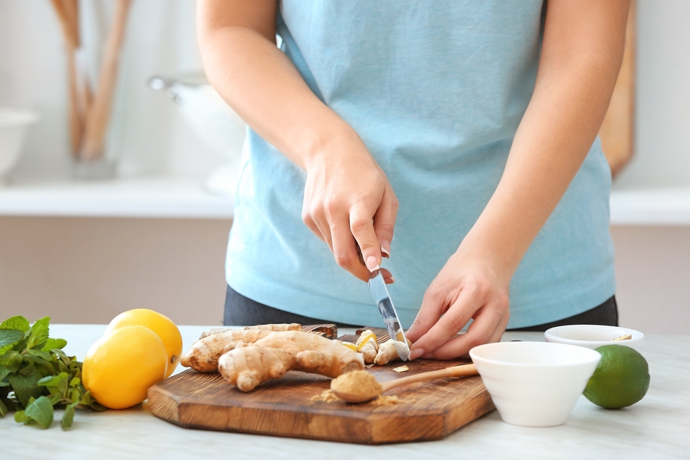 Woman,Cutting,Ginger,On,Table,In,Kitchen