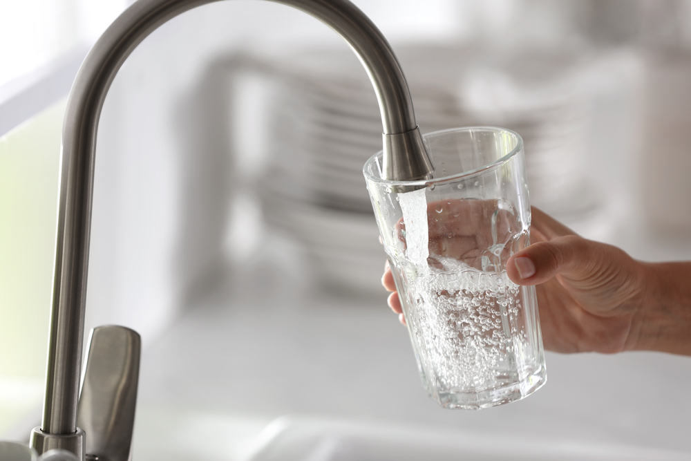 Woman,Pouring,Water,Into,Glass,In,Kitchen,,Closeup