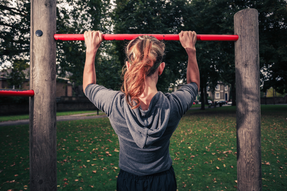 A,Young,Woman,Is,Doing,Pull,Ups,In,The,Park