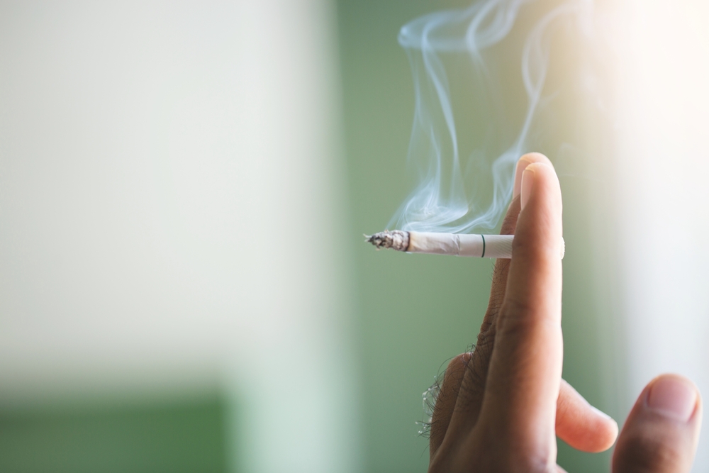 Man,Holding,Smoking,A,Cigarette,In,Hand.,Cigarette,Smoke,Spread.