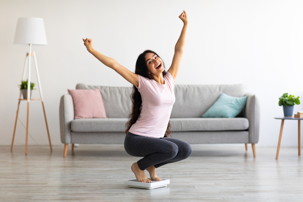 Excited,Indian,Woman,Sitting,On,Scales,,Raising,Hands,Up,,Happy