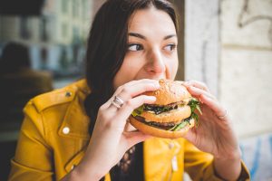 lunch,salad,held,american,beef,sauce,hamburger,hold,beautiful,burger,vitality,hunger,bbq,daylight,person,culinary,sesame,tasty,daytime,grill,woman,crispy,young,snack,guzzle,vegetables,holding,hungry,indoors,grilled,human,hand,limb,bread,ingredient,one,sandwich,eating,dinner,food,home,lifestyle,meal,mouth,meat,roasted,bun,millennial,fastfood;